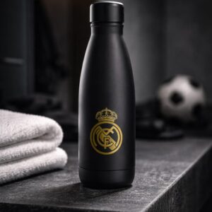 Botella de aluminio negra con detalles en dorado del Real Madrid, elegante y resistente. Ideal para llevar tus bebidas con estilo mientras muestras tu pasión por el club. Diseño oficial, ligera y perfecta para uso diario o como regalo para aficionados madridistas.